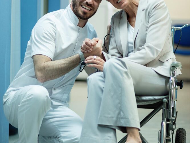happy-mature-woman-wheelchair-holding-hands-with-her-doctor-hospital-hallway happy mature woman wheelchair holding hands with her doctor hospital hallway